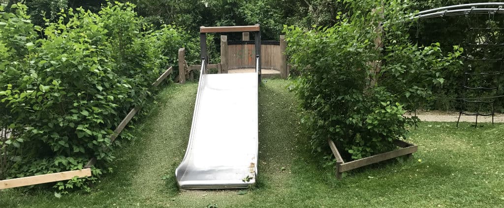 Toboggan dans une aire de jeux entouré de pelouse hybride